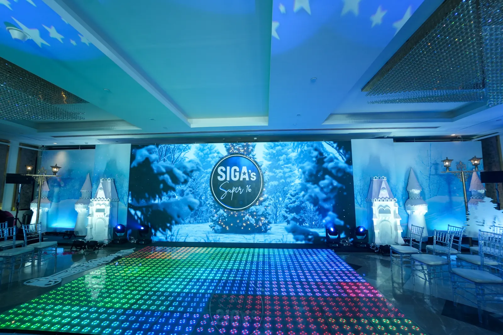 Winter wonderland stage with a snow forest LED backdrop, white castle towers, street lanterns and an RGB LED dance floor